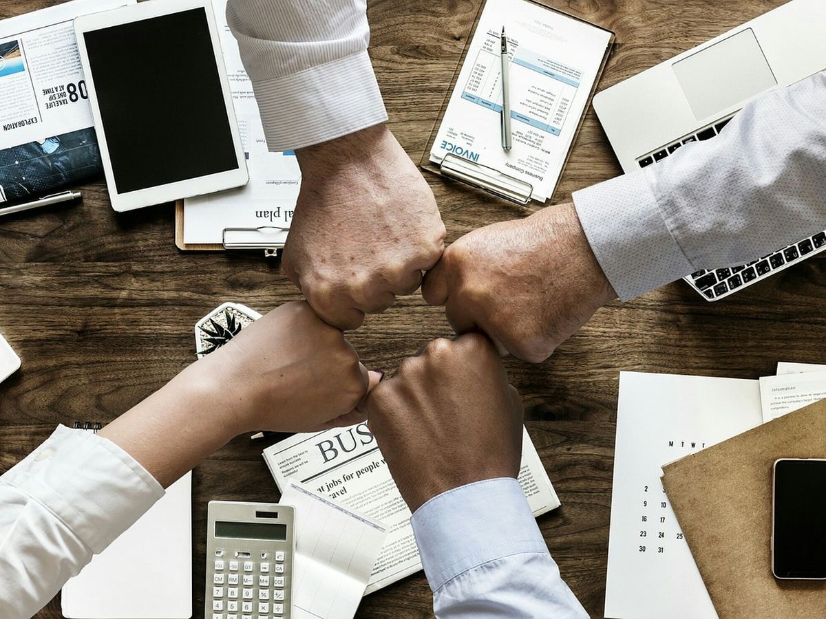 Manos de un equipo de trabajo unidas sobre una mesa de reunión